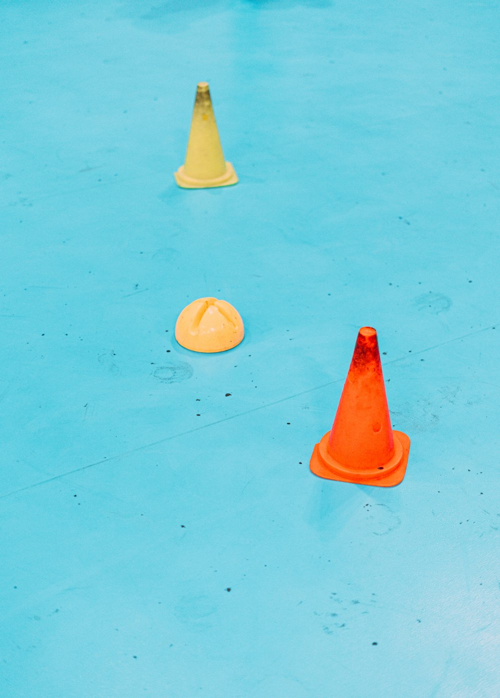 um grupo de cones laranja e amarelo sentados em cima de um chão azul