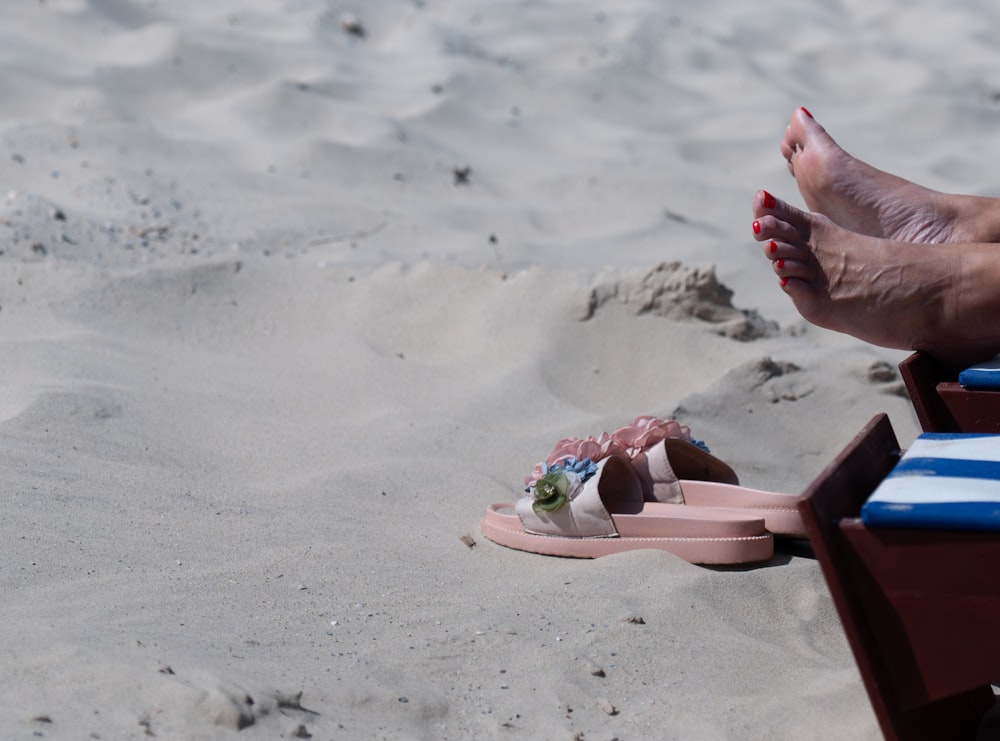 a person's feet sticking out of a pink sandal on a beach