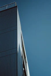 A sleek, modern building under construction against a gray sky, highlighting clean lines and structural detail.