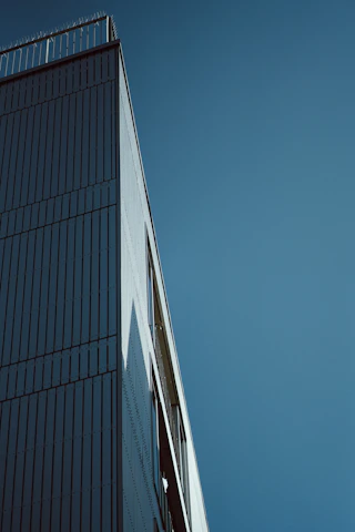A sleek, modern building under construction against a gray sky, highlighting clean lines and structural detail.
