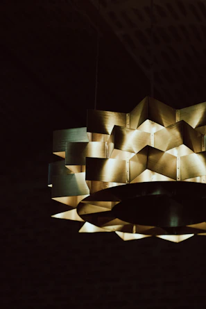 A geometric pendant light glowing warmly over a modern dining table.