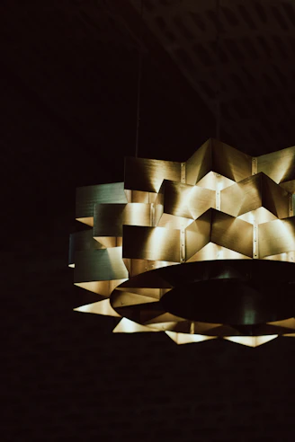A close-up of a modern, glowing pendant light with sleek metallic finishes.