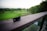 A credit card with Aeroplan branding is placed on a wooden railing, overlooking a lush green golf course. The scene includes well-maintained grassy areas, trees, and a soft, serene sky in the background.