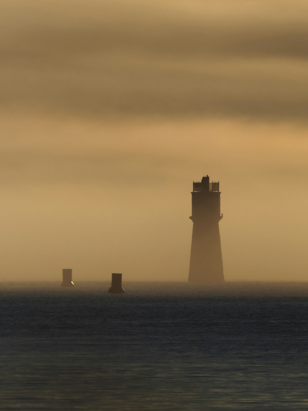 a light house in the middle of the ocean on a foggy day
