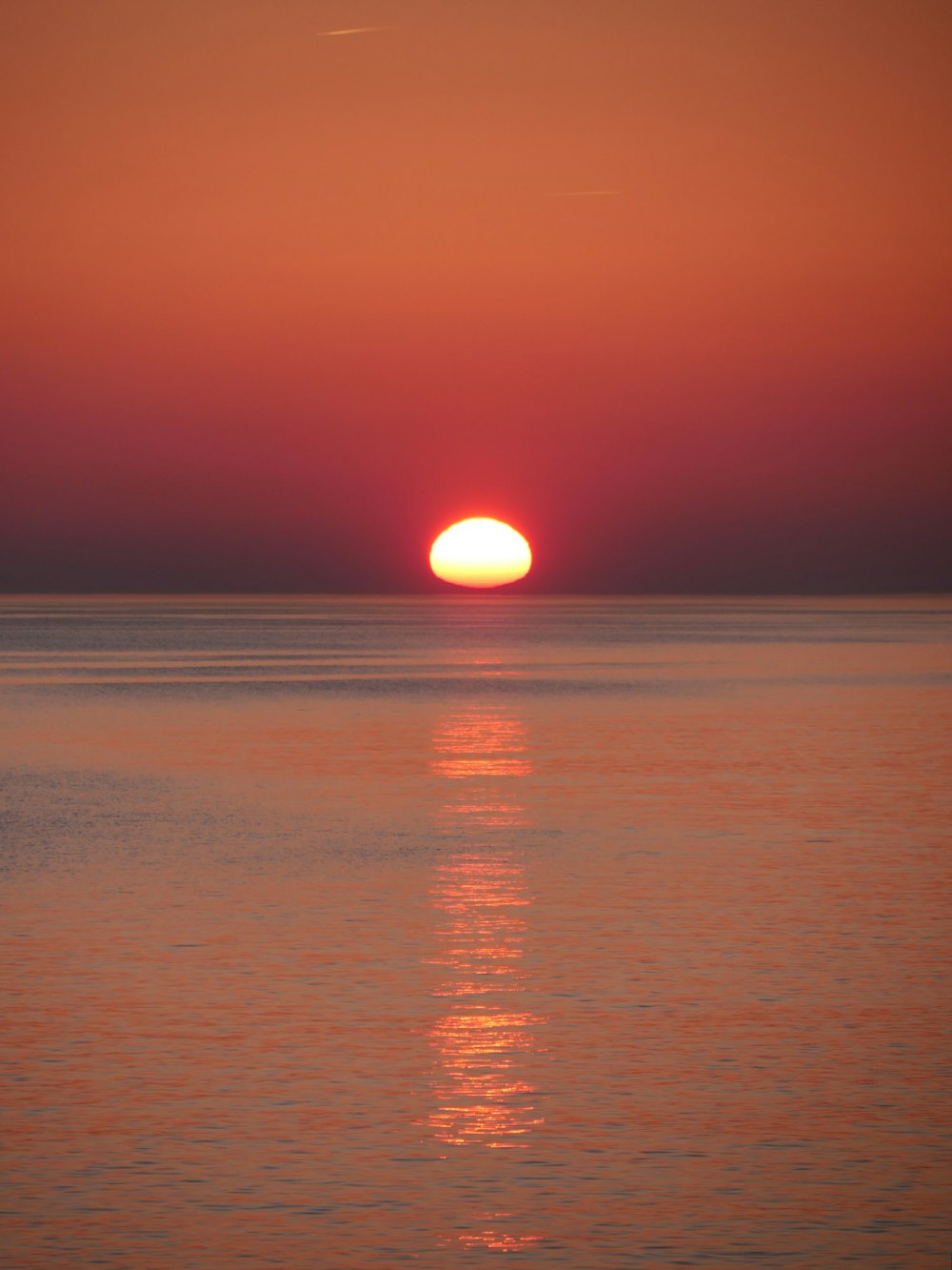 una gran masa de agua con una puesta de sol en el fondo