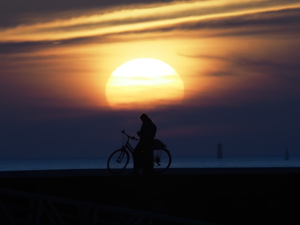 a person riding a bike in front of the sun