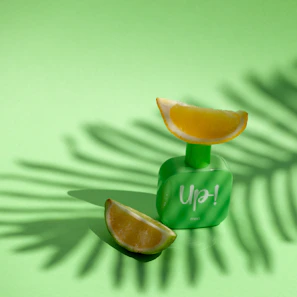 A fresh, citrus-scented perfume bottle with slices of lemon and green leaves around it.