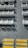 Rows of white benches casting distinct shadows on a gray, textured surface. The benches are arranged in orderly lines, suggesting a seating area. Bright yellow non-slip strips mark steps at the bottom of the image.