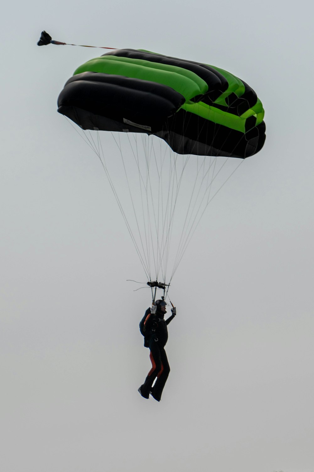 Um homem está parapenteando no céu com um paraquedas verde e preto