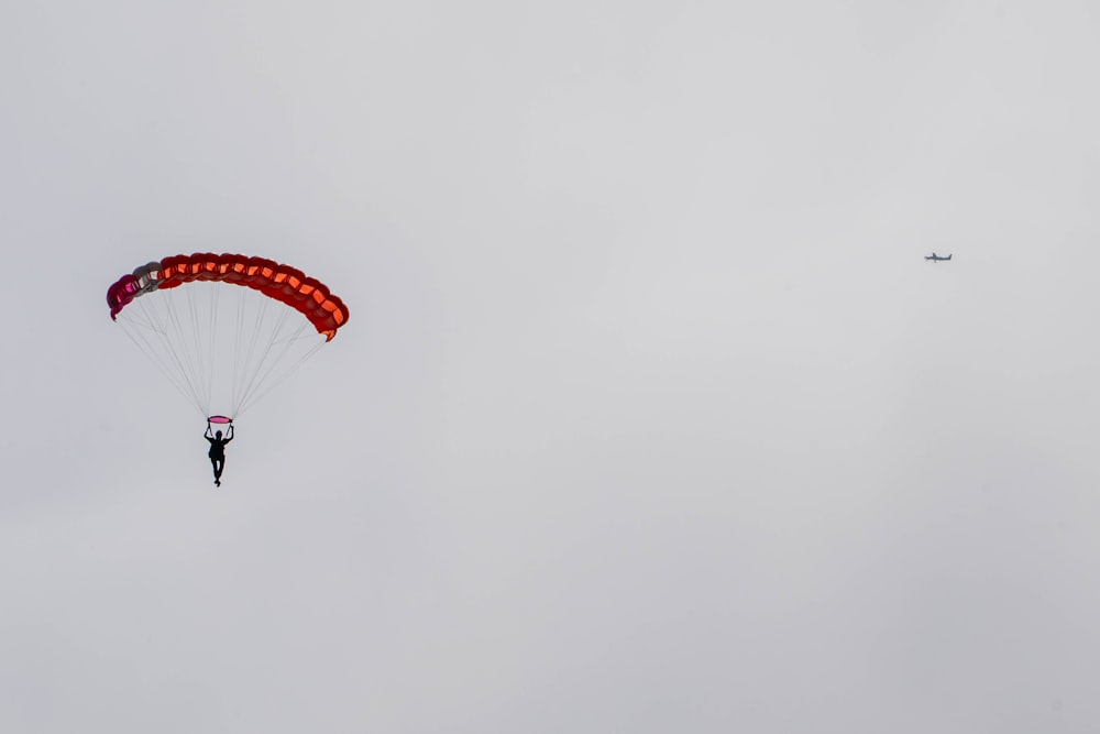 a person is parasailing in the sky with a plane in the background
