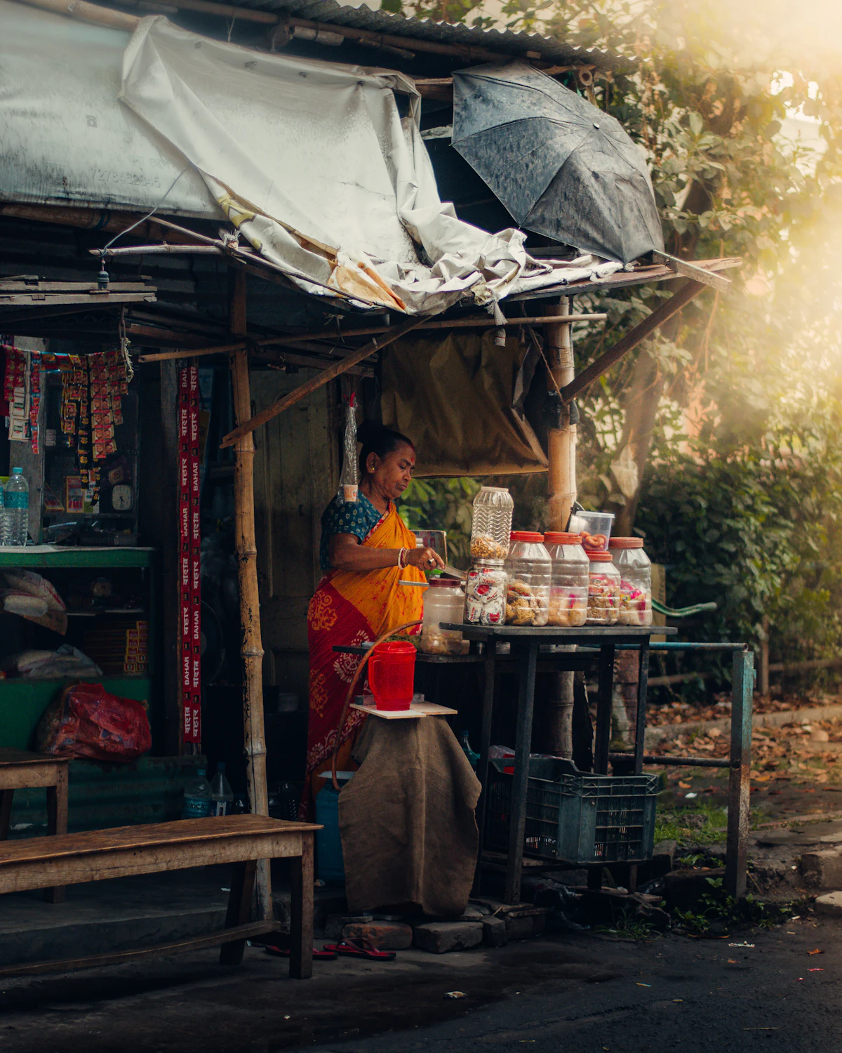 Seorang perempuan berdiri di depan warung kecil.