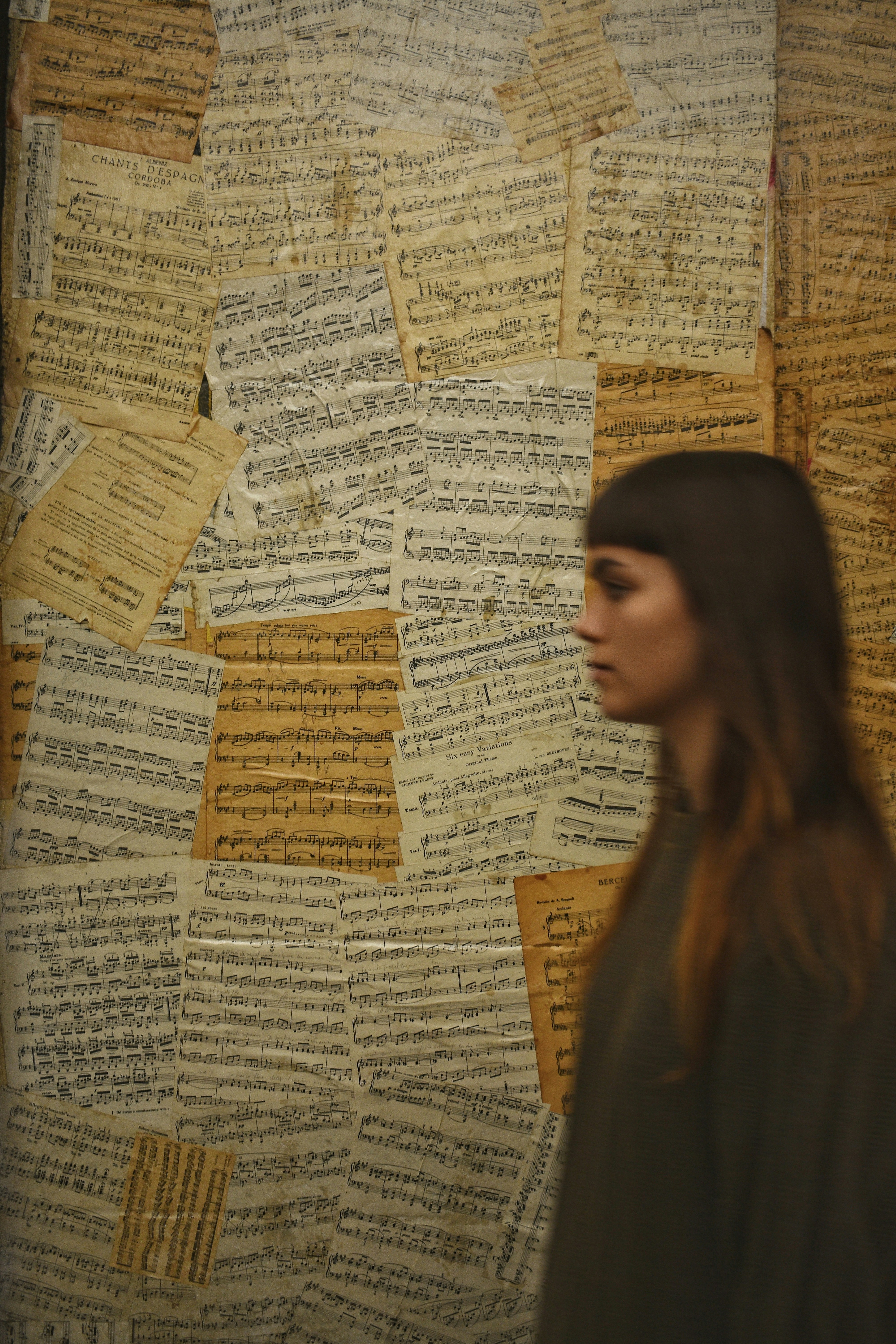 a woman standing in front of a wall covered in sheet music notes