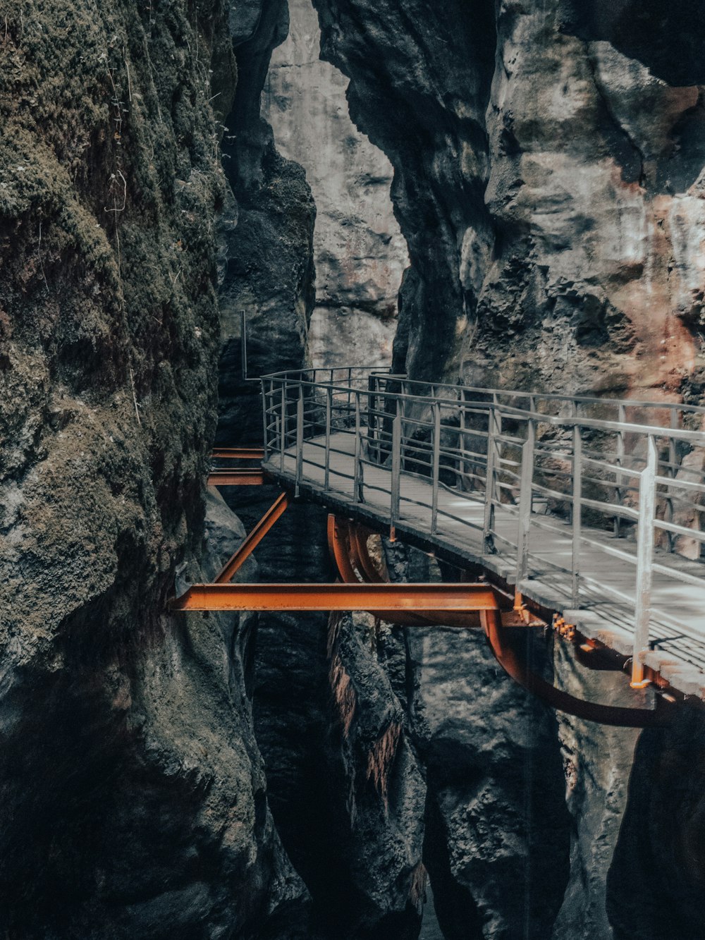 a wooden bridge over a narrow canyon in a mountain