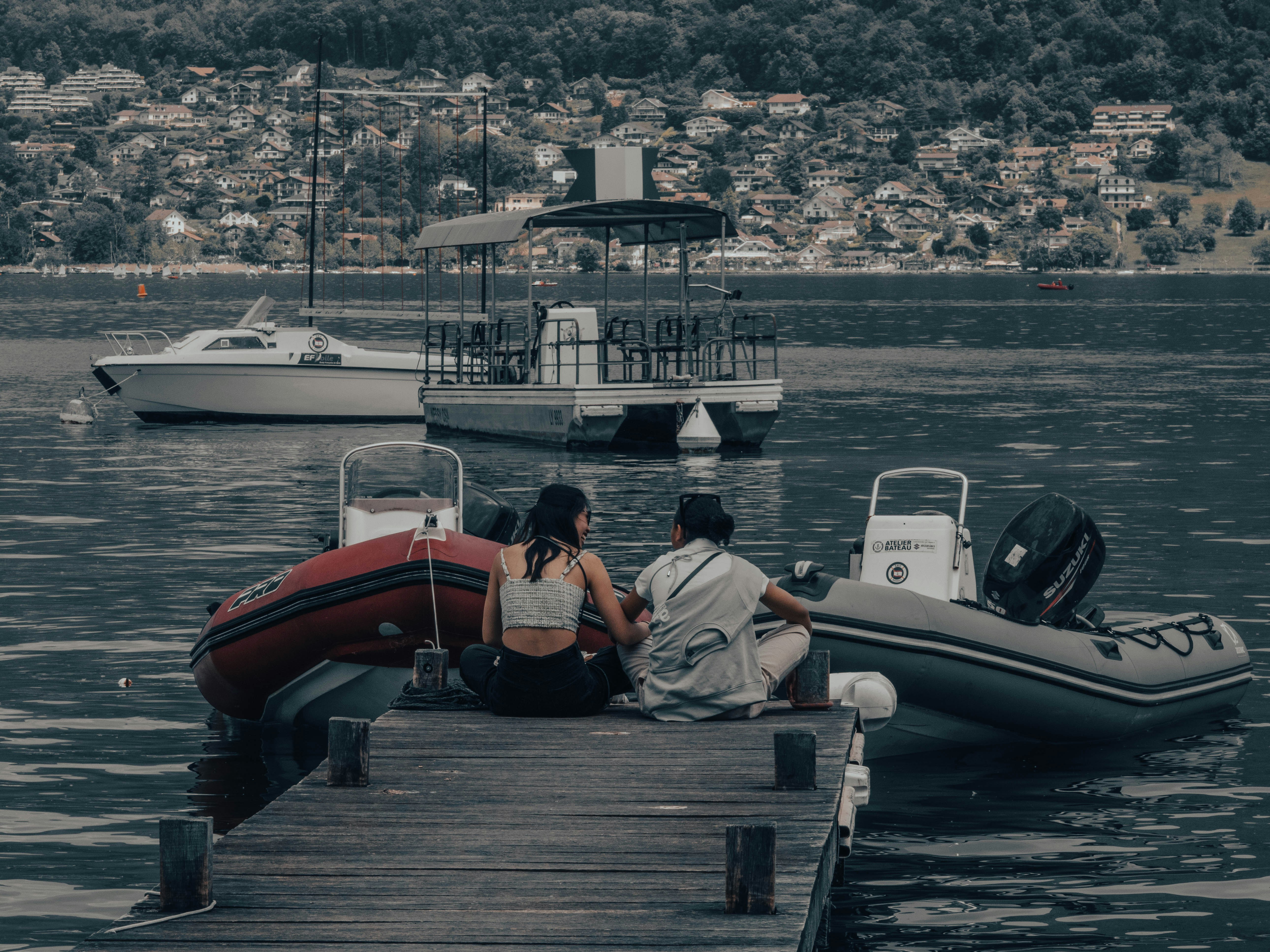 two people sitting on a dock next to a boat, 