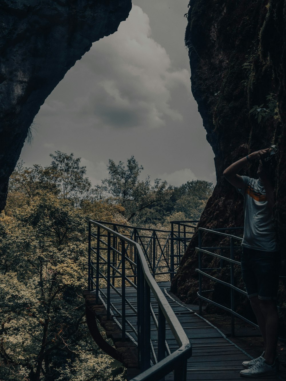 um homem em pé em uma passarela de madeira ao lado de uma caverna