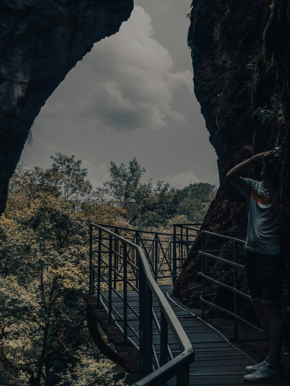 a man standing on a wooden walkway next to a cave