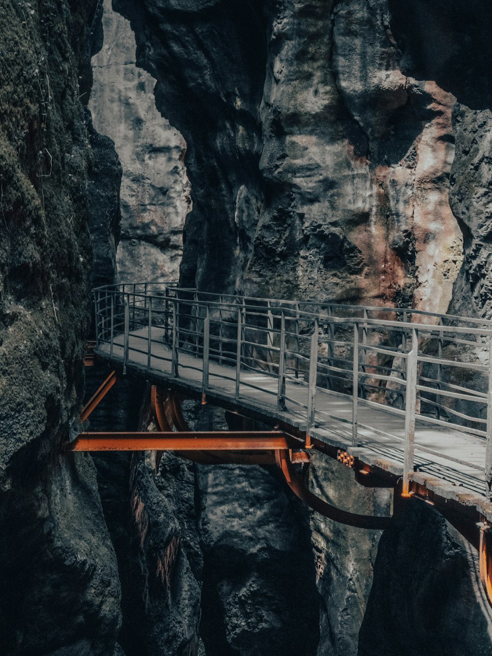 uma ponte de madeira sobre um cânion com uma cachoeira ao fundo