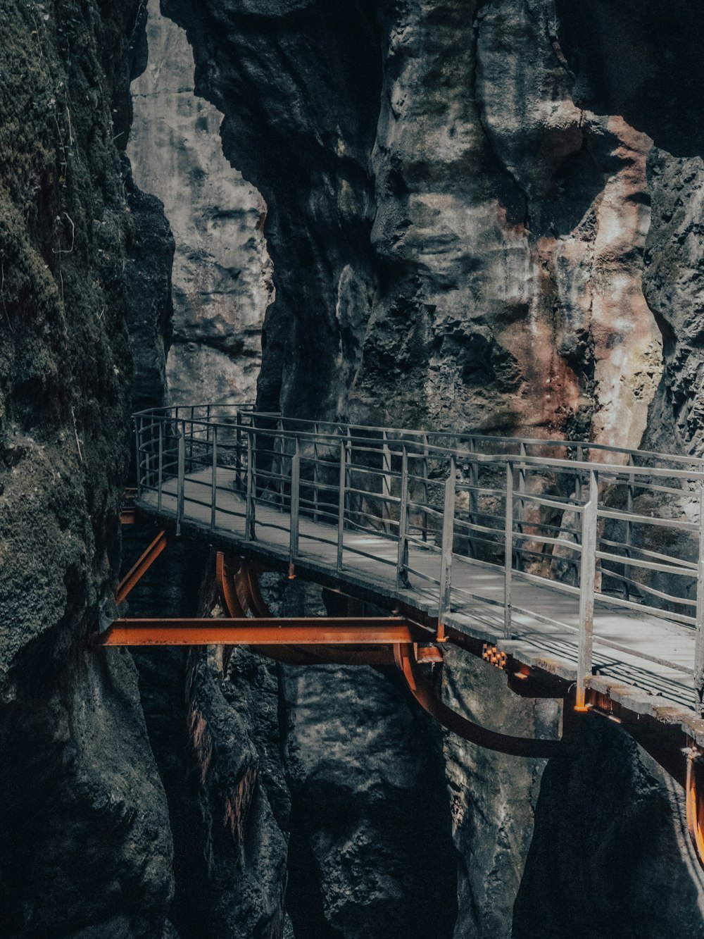 a wooden bridge over a canyon with a waterfall in the background