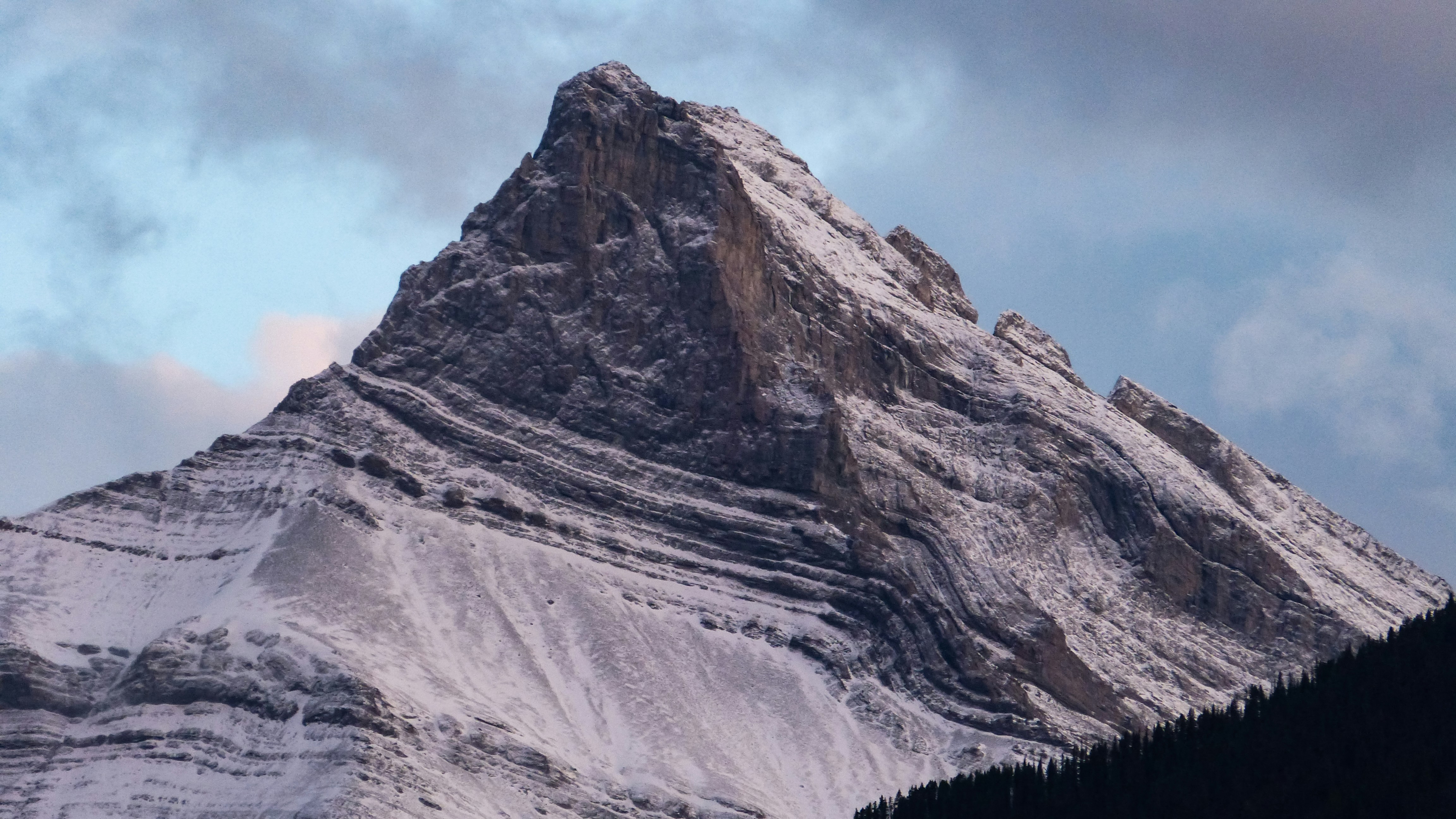 a very tall snow covered mountain under a cloudy sky