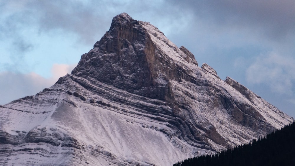 a very tall snow covered mountain under a cloudy sky