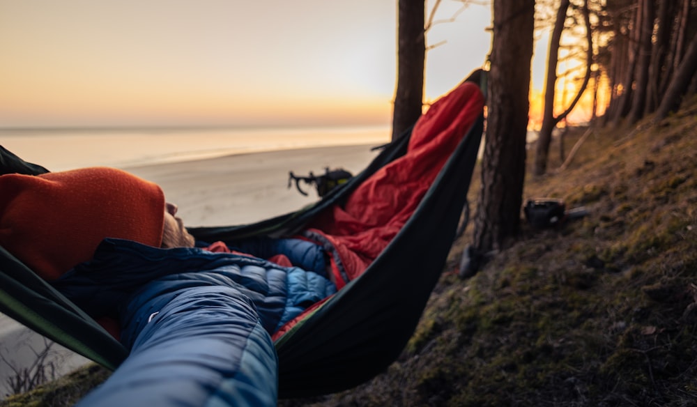 a person laying in a hammock on the beach