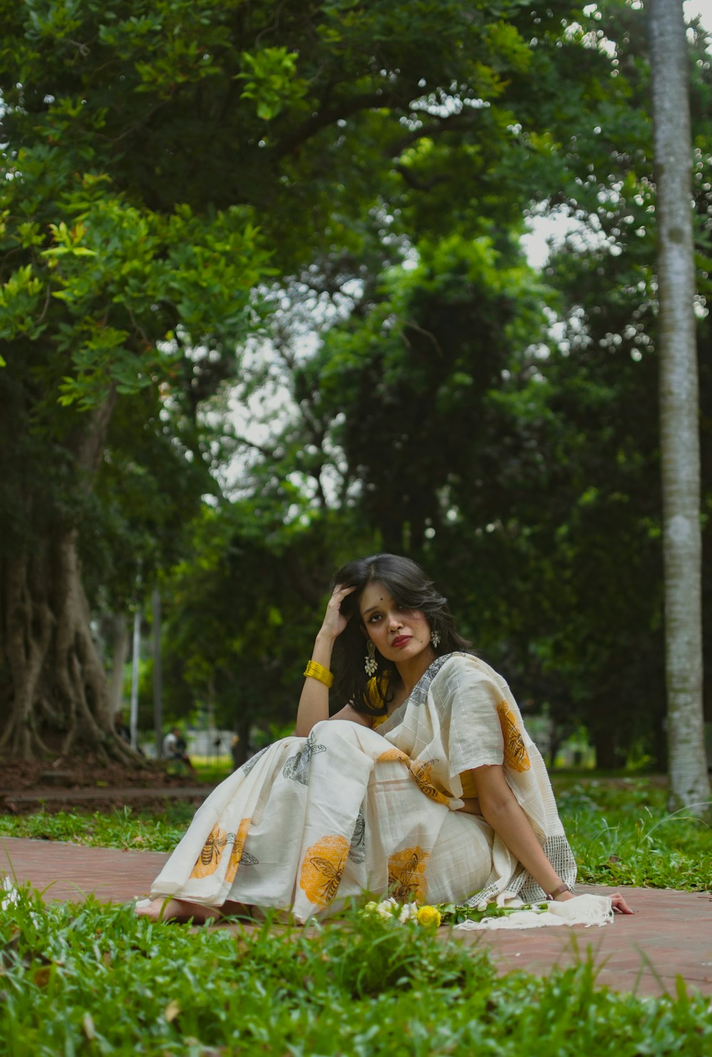 a woman sitting on the ground in a park