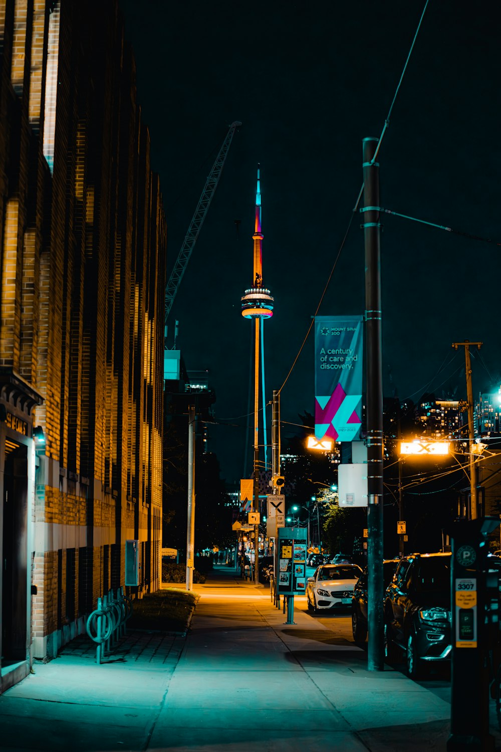 a city street at night with a tall tower in the background