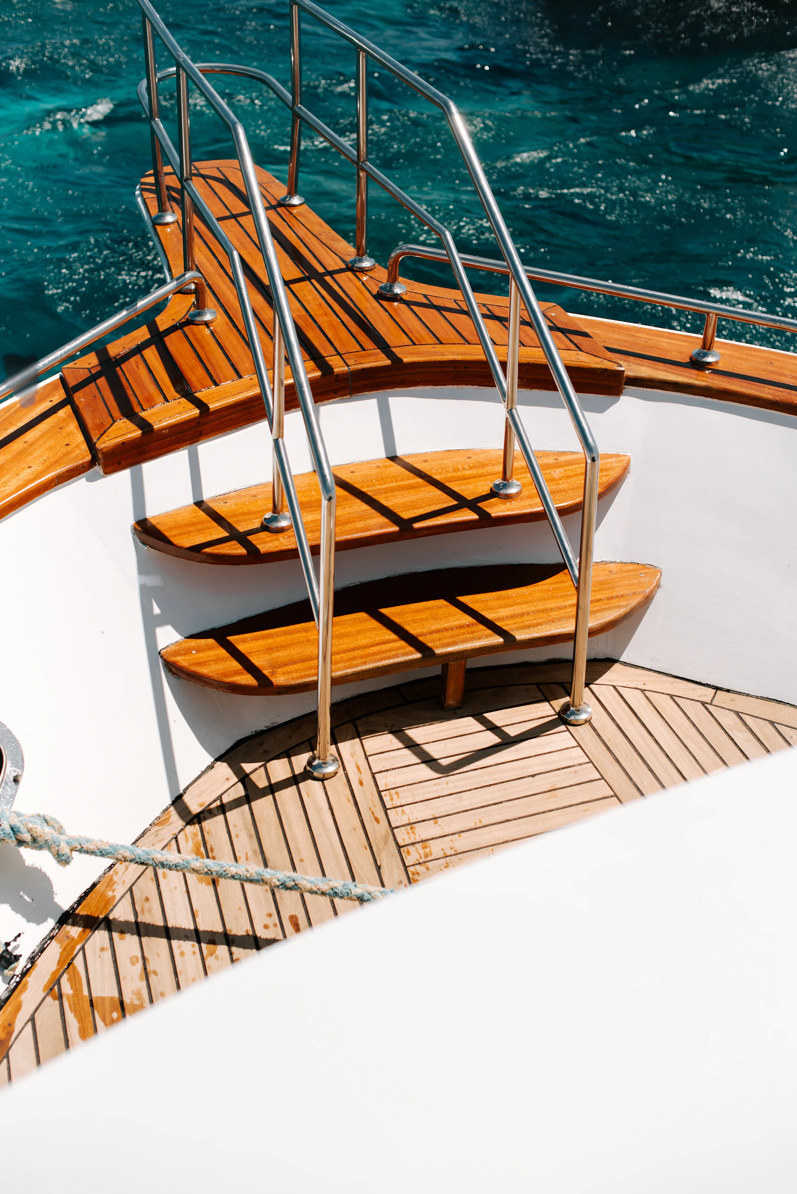 Polished teak deck stairs aboard a luxury yacht