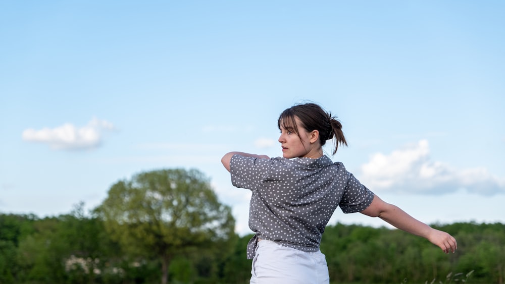 uma mulher está jogando um frisbee em um campo