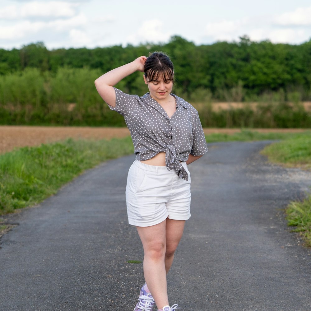 a woman walking down a road with her hands on her head