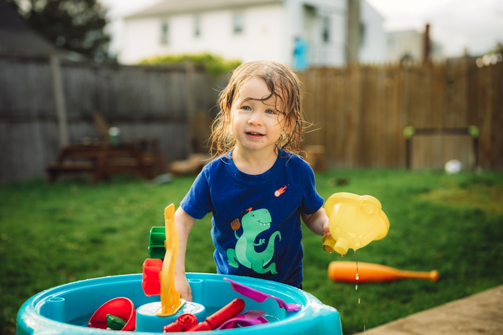 a little girl playing in a pool with toys