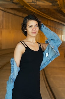 a woman in a black dress and jean jacket