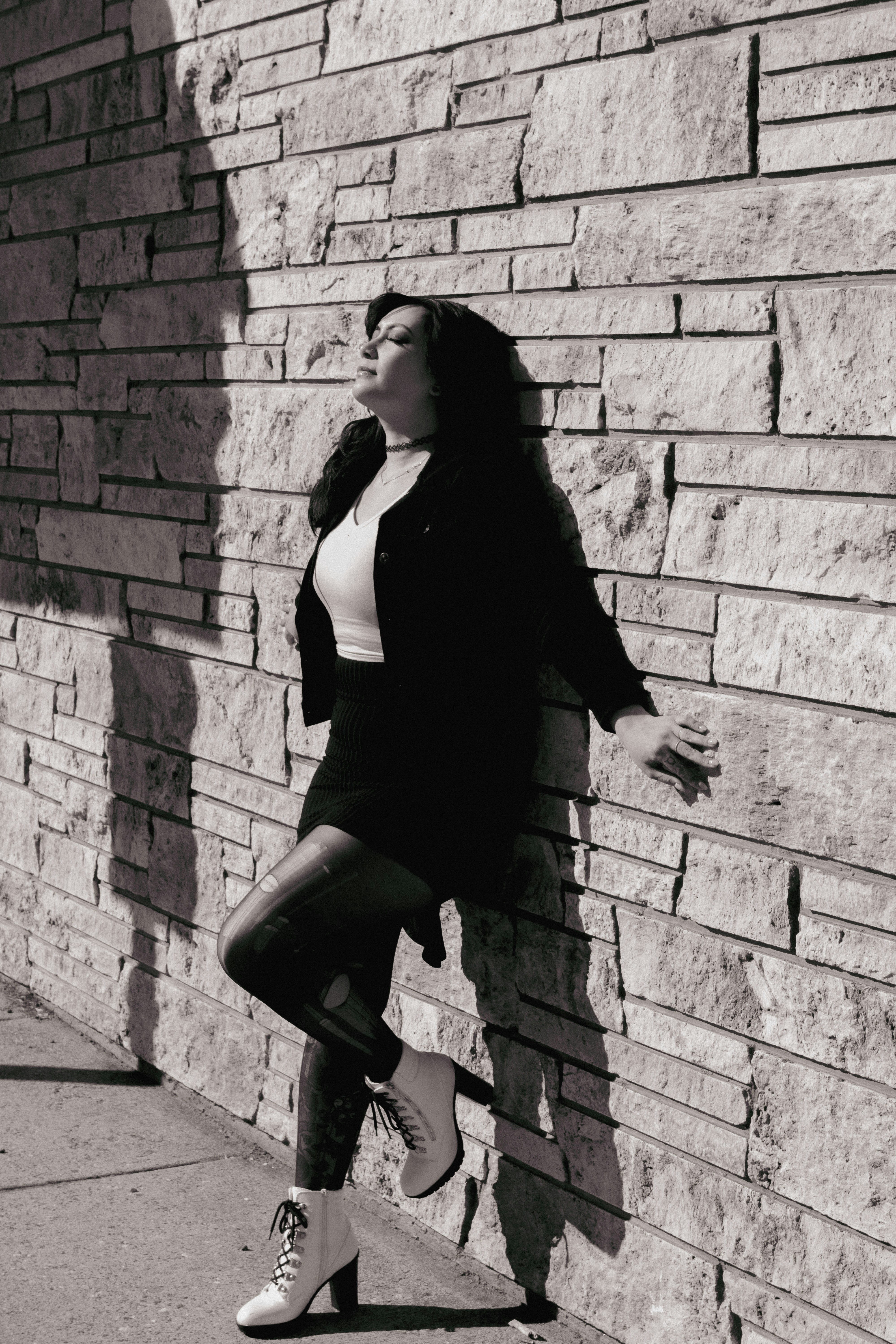A woman leaning against a brick wall photo – Free Woman Image on Unsplash