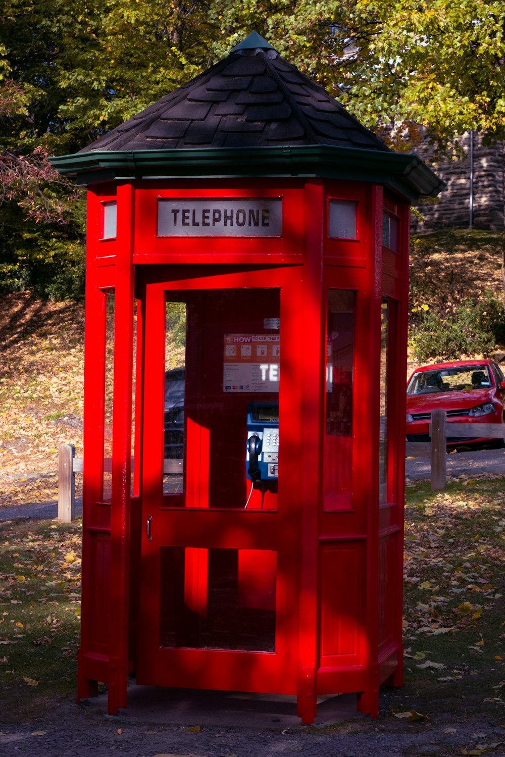 uma cabine telefônica vermelha sentada no meio de um parque