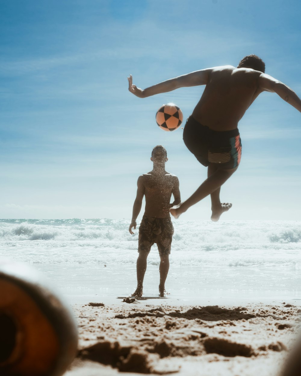 a couple of people on a beach with a ball