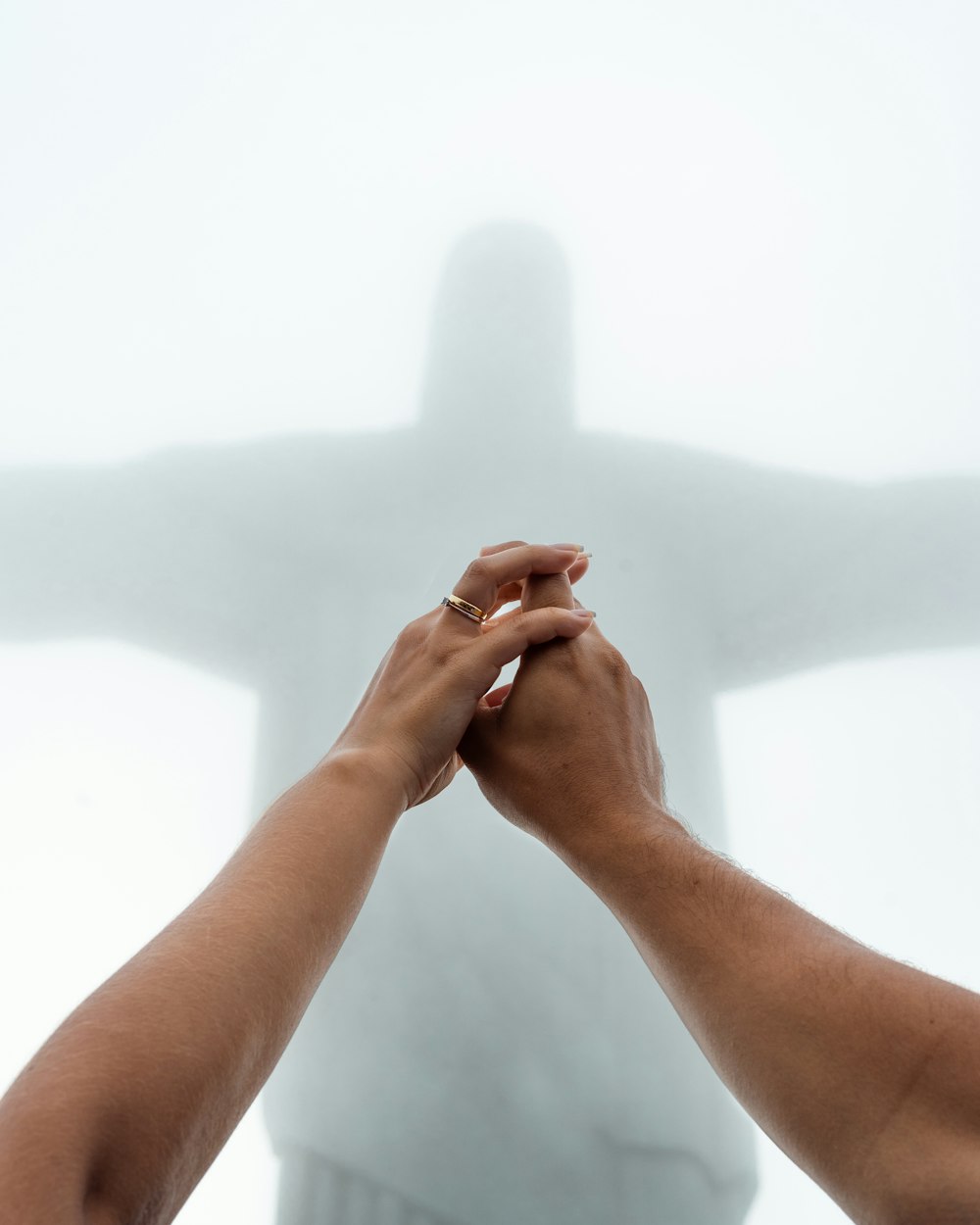 two people holding hands in front of a statue