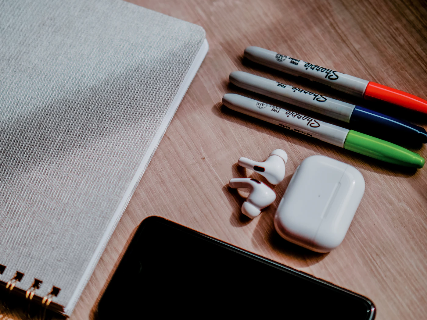 Phone, earbuds and small desk items arranged on a table