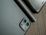 Close-up of a modern smartphone on a wooden desk with tech accessories.