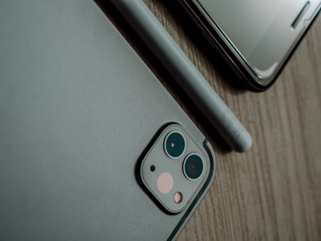 Close-up of a sleek new smartphone on a wooden desk with tech accessories around.