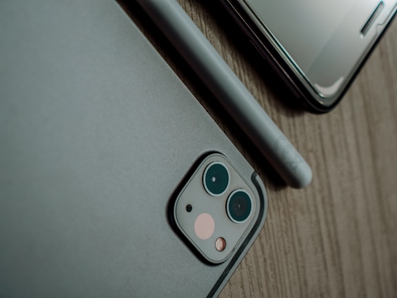 Close-up of a modern smartphone on a wooden desk with tech accessories.