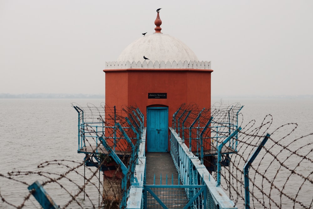 a red building with a blue door and a fence around it