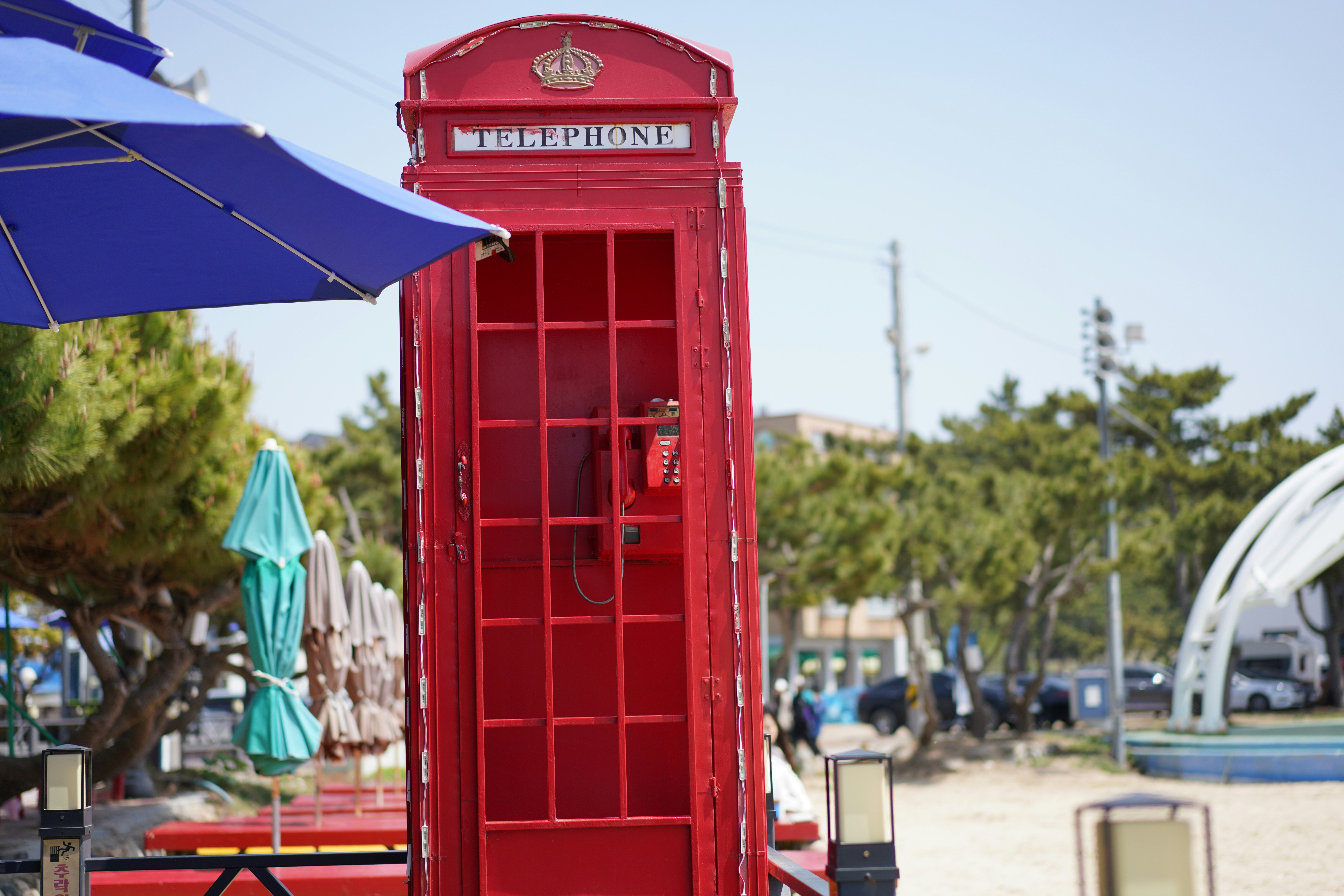 a red phone booth sitting on the beach