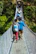Group of trekkers crossing a wooden bridge surrounded by lush green jungle in Gunung Leuser National Park.