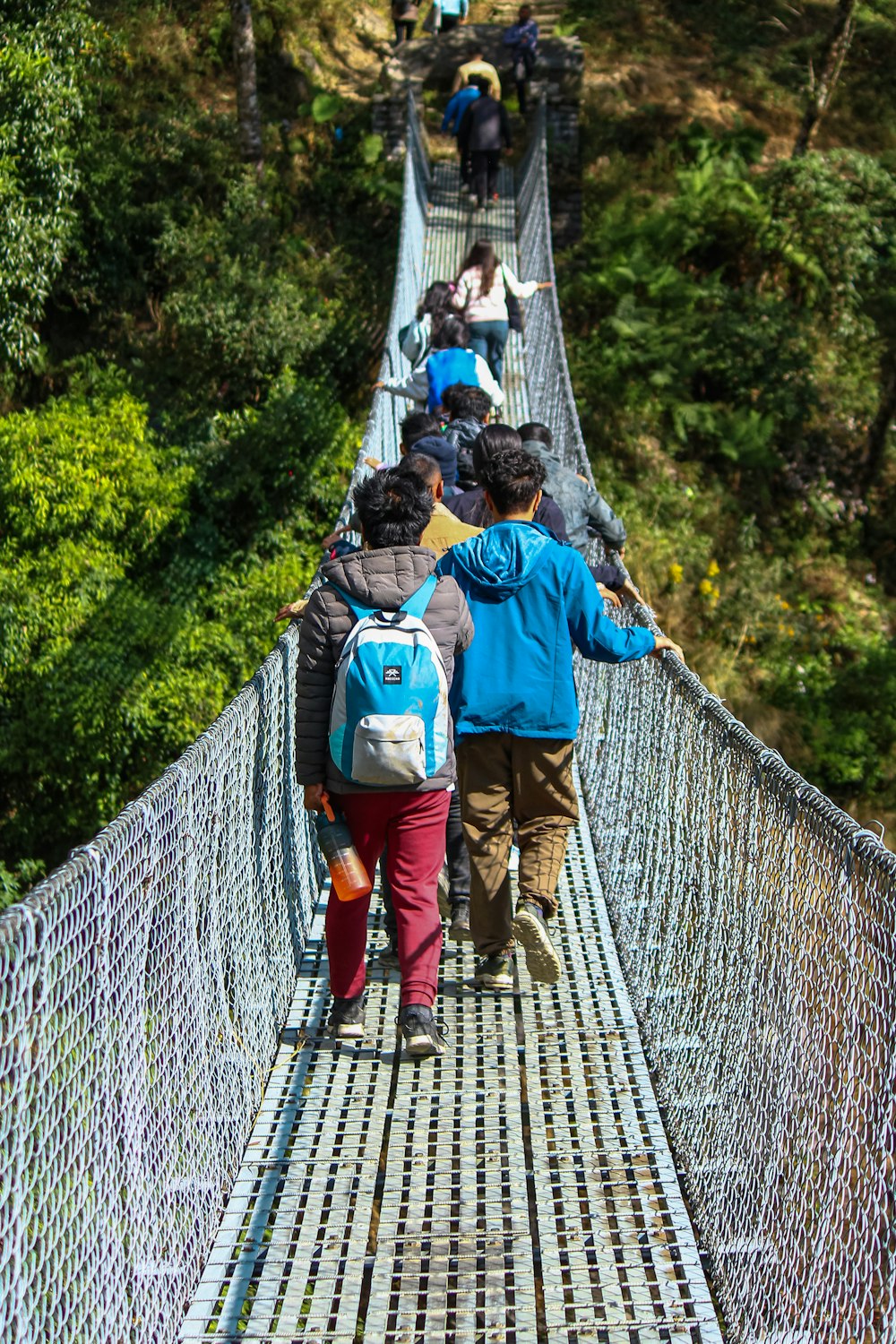 a group of people walking across a suspension bridge