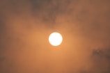 A bright sun is positioned in the center of the image, surrounded by a dense layer of clouds. The atmosphere appears hazy with a warm, orange glow enveloping the scene.