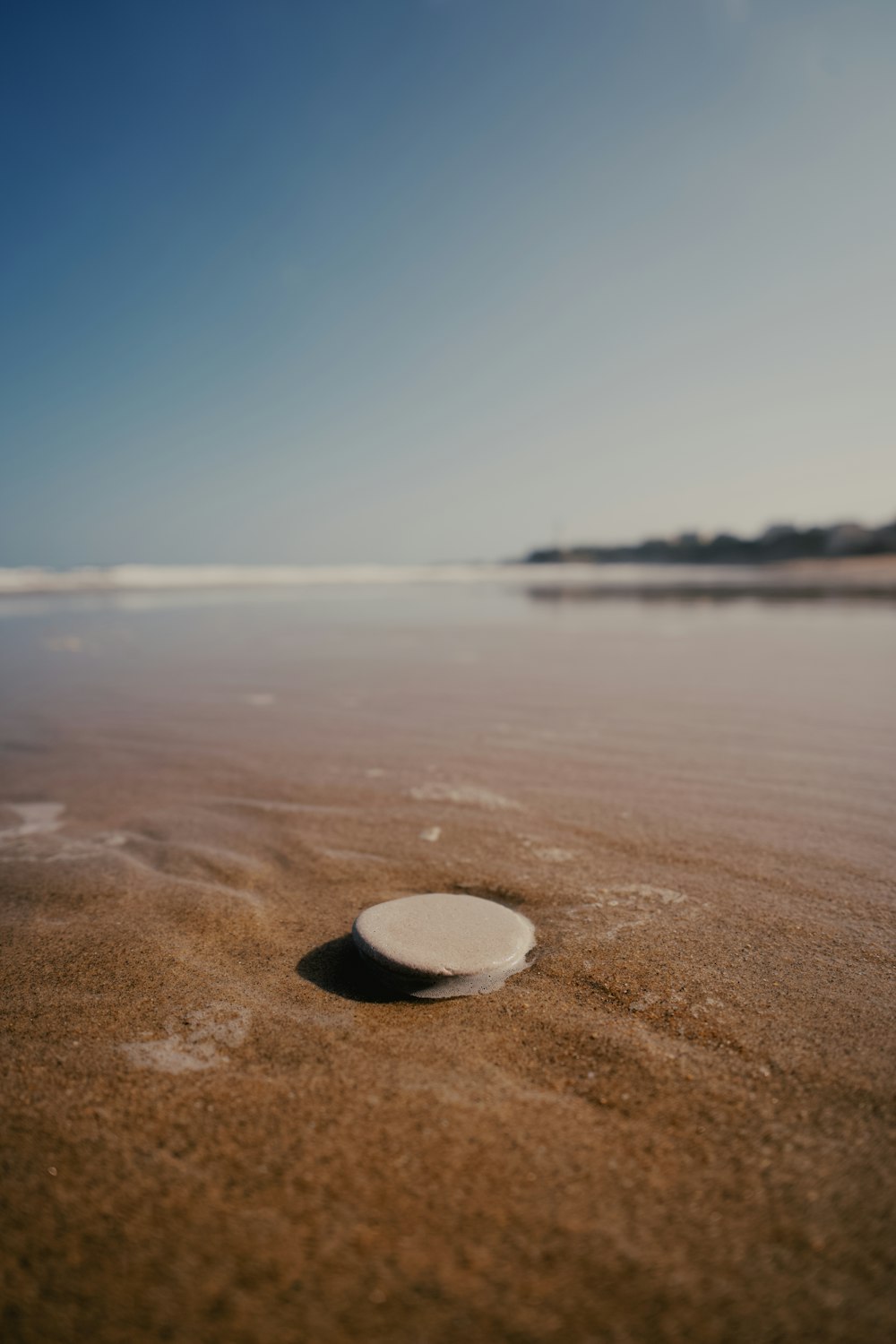 eine weiße Scheibe, die auf einem Sandstrand sitzt