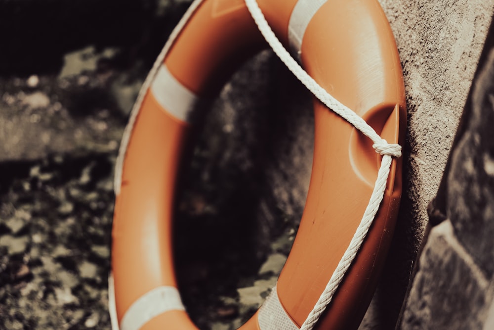 an orange life preserver tied to a stone wall
