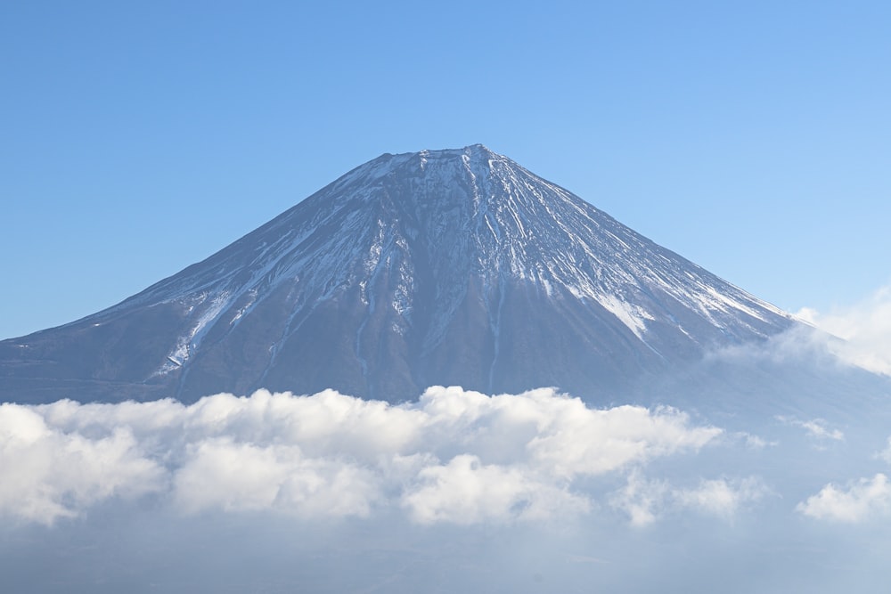 a mountain covered in snow surrounded by clouds