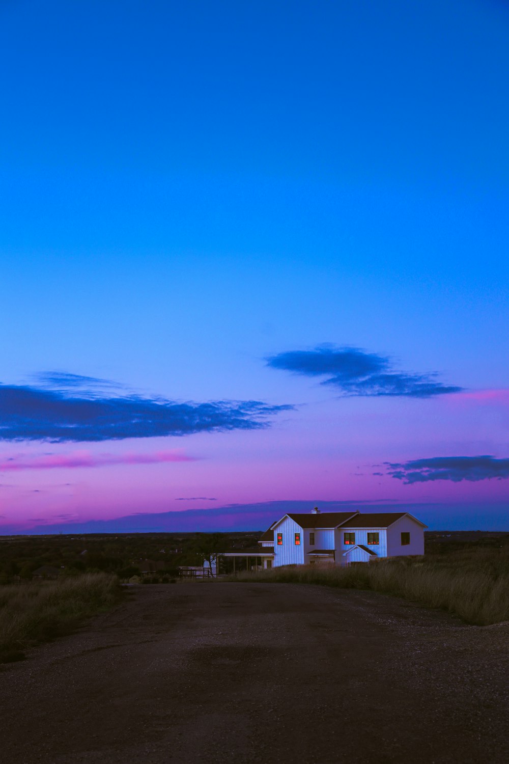 a white house sitting on the side of a dirt road