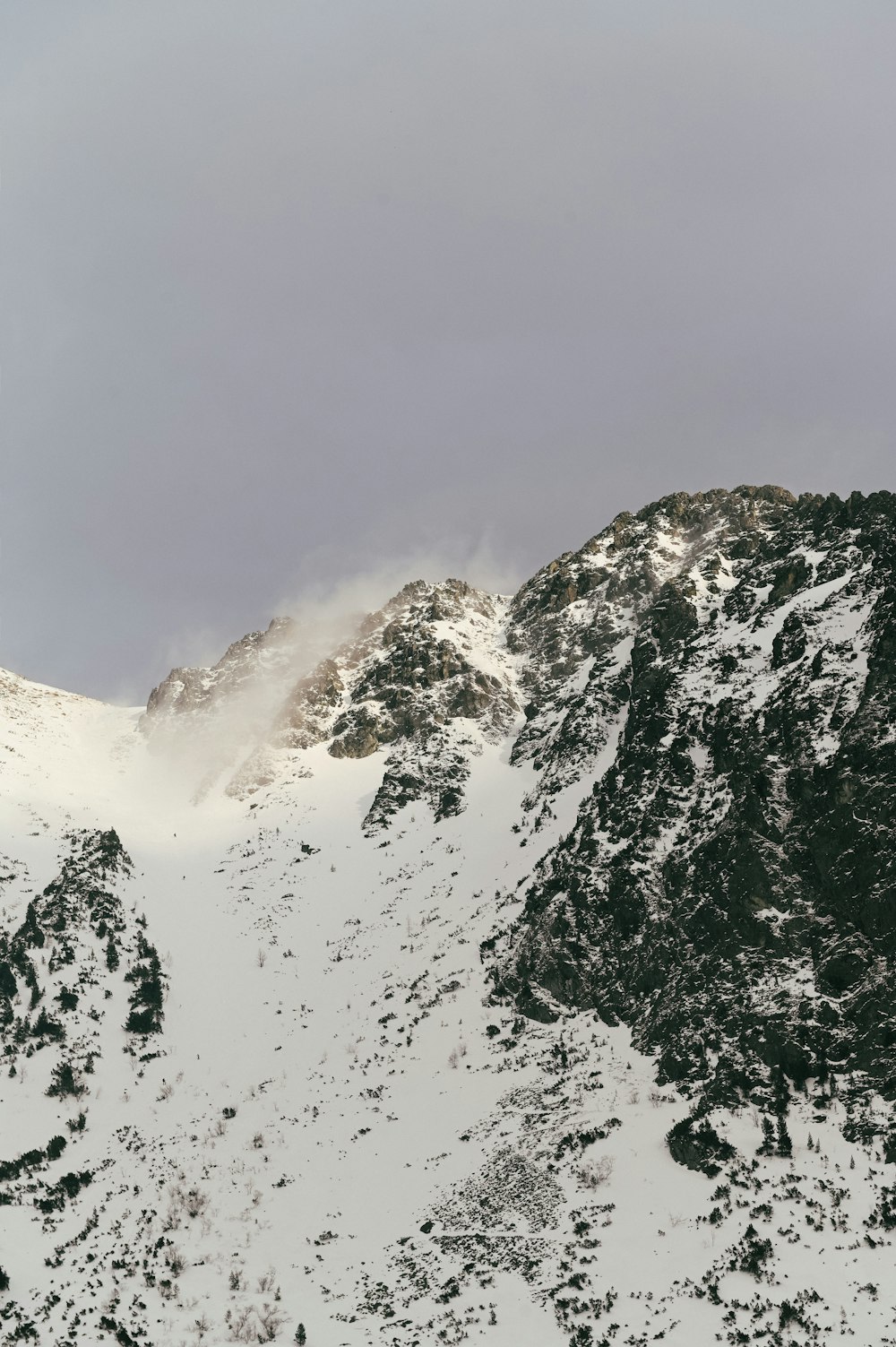 空に雲が積もった雪に覆われた山
